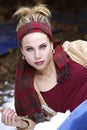 A gorgeous blond woman with a red plaid scarf around her head in the winter.