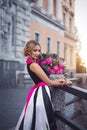 A gorgeous blonde girl in a couture fashion dress with pink peonies and black and white stripes