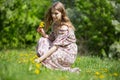 A gorgeous girl collects a bouquet of the first flowers in the Park