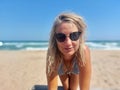 Blonde girl with sunglasses in bikini posing on the beach Royalty Free Stock Photo