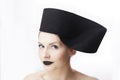 Gorgeous blonde woman model with blue eyes and black lipstick wearing big stylish designer black unique hat/ headpiece