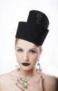 Gorgeous blonde woman model with blue eyes and black lipstick wearing big stylish designer black unique hat/ headpiece