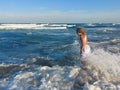 Gorgeous blonde woman in white dress on the beach with sea waves