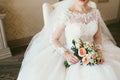 Gorgeous bouquet of white and orange flowers in the hands of the charming woman in a white dress. Bride sit on the chair Royalty Free Stock Photo