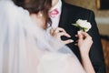 Gorgeous bride in amazing gown putting on white peony boutonniere groom suit. Beautiful woman getting ready in the morning. Royalty Free Stock Photo