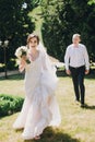 Gorgeous bride in amazing gown and stylish groom running and laughing in sunny park. Beautiful happy wedding couple enjoying time Royalty Free Stock Photo