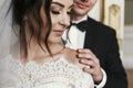 Gorgeous bride with bouquet and stylish groom gently hugging in luxury room in hotel. rich wedding couple embracing. romantic Royalty Free Stock Photo