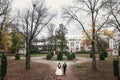 Gorgeous bride with bouquet and stylish groom walking at old castle in european park in autumn time. happy wedding couple Royalty Free Stock Photo