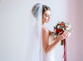 Gorgeous bride in classy dress poses with a red wedding bouquet of roses and peonies Royalty Free Stock Photo