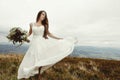 gorgeous bride dancing and having fun holding dress, boho wedding, luxury ceremony at mountains