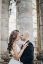 Gorgeous bride and groom embracing in evening sunlight near old castle in park. Romantic moment. Stylish wedding couple gently Royalty Free Stock Photo