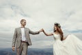 Gorgeous bride and groom holding hands and dancing at sky and cl Royalty Free Stock Photo