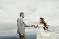 Gorgeous bride and groom holding hands and dancing at sky and cl Royalty Free Stock Photo