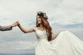 Gorgeous bride and groom holding hands and dancing at sky and cl Royalty Free Stock Photo