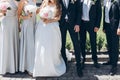 gorgeous bride with peony bouquet and stylish groom with bridesmaids and groomsmen posing in sunny garden for photo. luxury