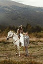 Gorgeous bride riding a white horse and stylish groom, boho wed Royalty Free Stock Photo