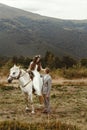 Gorgeous bride riding a white horse and stylish groom, boho wed Royalty Free Stock Photo