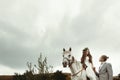 Gorgeous bride riding a white horse and stylish groom, boho wed Royalty Free Stock Photo