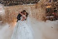 Gorgeous bride and stylish groom dancing under golden confetti at wedding reception. Royalty Free Stock Photo