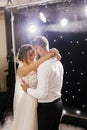 Gorgeous bride and stylish groom gently dancing at wedding reception. Happy wedding couple performing first dance in restaurant. Royalty Free Stock Photo