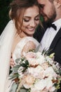 Gorgeous bride and stylish groom gently hugging and smiling on b