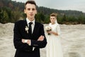 Gorgeous bride and stylish groom holding hands and looking at sandy beach lake, true emotions, luxury wedding Royalty Free Stock Photo