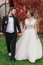 Gorgeous bride and stylish groom holding hands and walking at wa Royalty Free Stock Photo