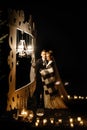 Gorgeous bride and stylish groom hugging at  romantic candle light arch under blanket at evening wedding ceremony, gentle moment Royalty Free Stock Photo