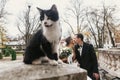 Gorgeous bride and stylish groom  walking near cute black and white cat in european city street in autumn. happy wedding couple Royalty Free Stock Photo