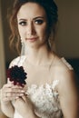 Gorgeous bride in vintage lace white wedding dress holding red flower, portait of beautiful woman posing near a window, wedding Royalty Free Stock Photo