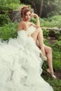 Gorgeous bride woman with long legs in a lush wedding dress.