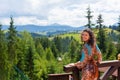A gorgeous brunette girl enjoy beauty of nature standing on terrace with breathtaking mountain landscape view