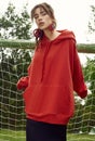 Gorgeous brunette woman in fashion red hoodie on sports field