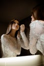 Gorgeous brunette woman with long hair and blue eyes looking herself in the mirror and doing makeup Royalty Free Stock Photo