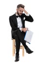 Businessman sitting and holding clipboard while slapping forehead