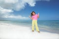 Gorgeous charming little girl standing and holding her hands up on Cuban beach against turquoise ocean and blue sky background Royalty Free Stock Photo