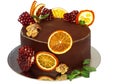Gorgeous chocolate cake decorated with slices of baked orange and fresh pomegranate with a sprig of mint on an isolated white back Royalty Free Stock Photo