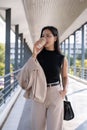 A gorgeous Asian businesswoman is going work, having a morning coffee while walking on a skywalk Royalty Free Stock Photo