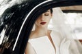 gorgeous elegant bride posing in stylish retro black car, sitting inside in saloon. luxury wedding in vintage style. portrait