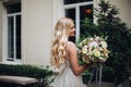 Gorgeous bride with wedding flowers boquet posing outdoors, against luxury house. Royalty Free Stock Photo