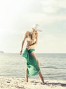 Beautiful, attractive, young woman in a hat and white bikini with green silk on a beach. Resort, vacation, concept. Royalty Free Stock Photo