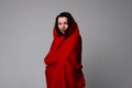 Gorgeous emotional dark-haired young woman in red cloth, standing over gray background