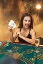 Gorgeous young woman sitting at poker table with glass of champagne