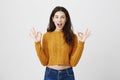 Gorgeous european female raising hands with ok gesture, standing with opened mouth and widened eyes, expressing