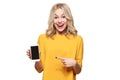 Gorgeous excited woman pointing to blank screen on mobile phone over white background, celebrating victory and success. Excitement Royalty Free Stock Photo