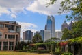 A gorgeous garden landscape with red flowers and lush green trees and plants with skyscrapers and office buildings in the city