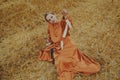 A gorgeous girl in a long dress sits on a wheat field. Blonde posing for fashion photo. Gentle model dancing Royalty Free Stock Photo