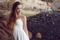 Gorgeous girl in a long white dress on the ocean at the beach. The model is inherited by nature. Girl on vacation, light dress, su