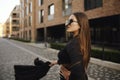 Gorgeous girl walks about the city. Brunette with long hair in a black dress and leather. Girl, fashion photo, street fashion. Royalty Free Stock Photo