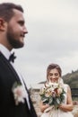 Gorgeous happy bride with modern bouquet looking at stylish groom and smiling outdoors. Sensual wedding couple posing. Romantic m